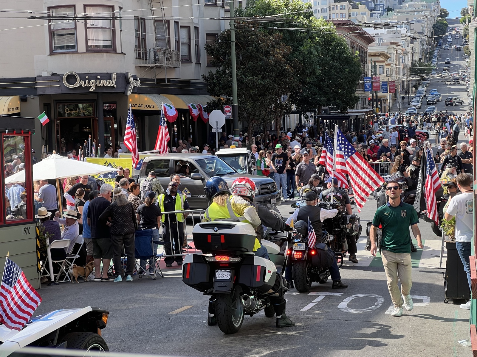 Motorcycle procession moving through a crowded San Francisco street during the Italian Heritage Festival